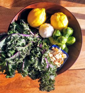 kale, brussels sprouts, lemon, garlic placed in a wooden bowl